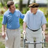 Man walks with the assistance of a walker and a home care specialist
